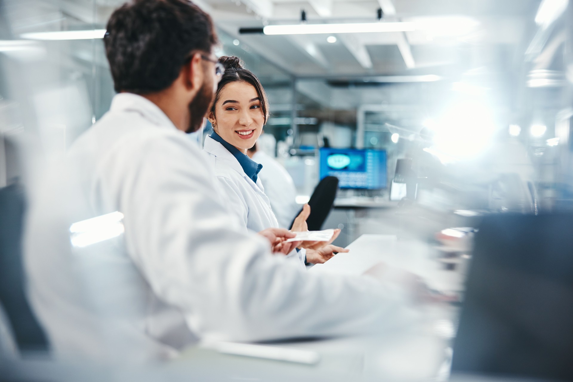 Laptop, scientist and colleagues with smile, medical research and talking for results of test and discussion. Lab, online and conversation for medicine of healthcare, pharmaceutical and collaboration